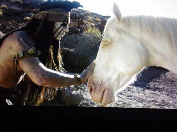 Tonto (Johnny Depp) wearing crow crown, touching Silver (played by Silver an 11 yr old quarter horse - upstaging everyone), a white spirit horse, The Lone Ranger, film, Northgate, Seattle, Washington, USA