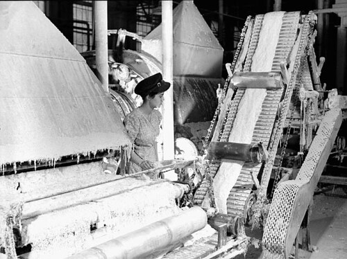 The operator, Clémence Gagnon, watches a machine carding asbestos fibre, Johns Manville factory, Asbestos, Que., 1944 / L’opératrice, Clémence Gagnon, observe la machine à carder les fibres d’amiante, usine Johns Manville, Asbestos, Qc, 1944